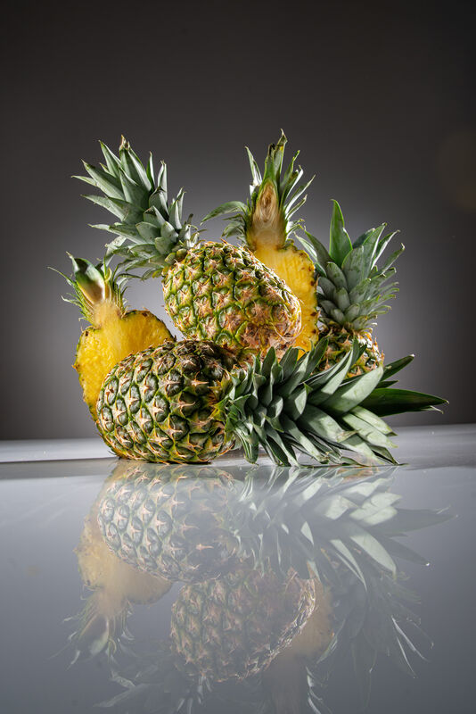 Stehende und liegende Ananas neben geschnittener Ananas