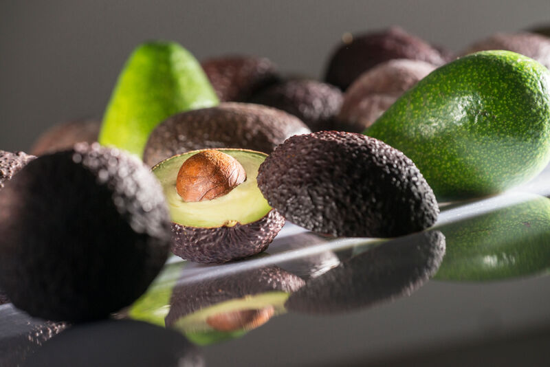 Liegende und stehende Avocados mit aufgeschnittener Avocado in der Mitte