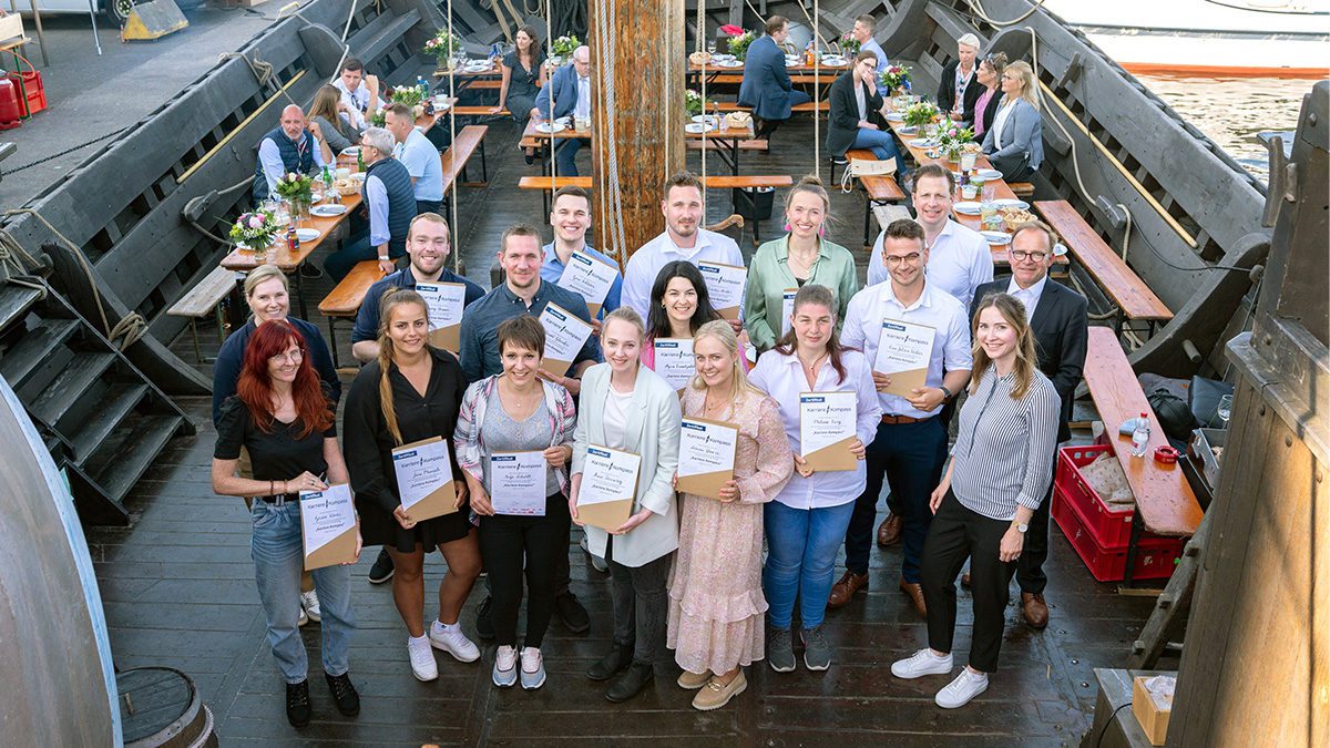 Eine Gruppe Bartels-Langness Mitarbeiter die auf einem Schiff stehen und Urkunden in den Händen halten.