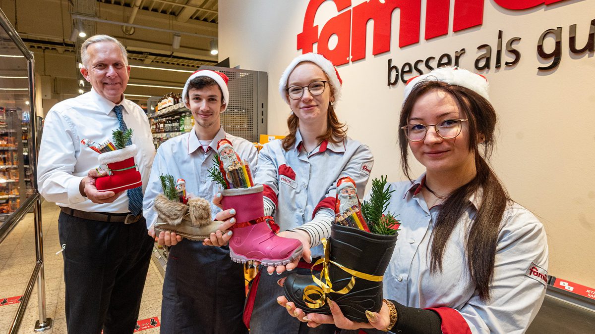 Drei Azubis und ein Mann die Nikolausstiefel halten und Weihnachtsmützen tragen.