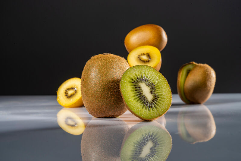 halbierte Kiwi vor stehenden ganzen und halbierten Kiwis