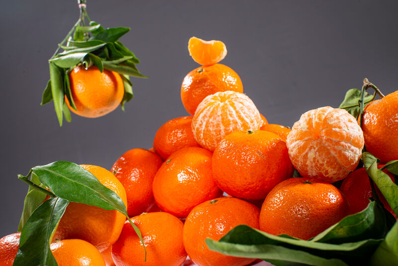 geschälte Mandarine auf Haufen Mandarinen mit Blättern