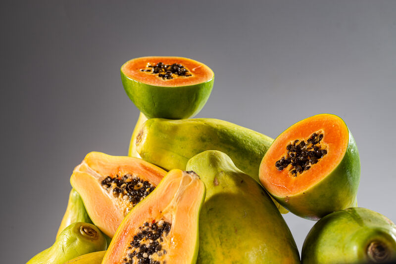 halbierte Papaya auf mehreren ganzen und halbierten Papayas liegend