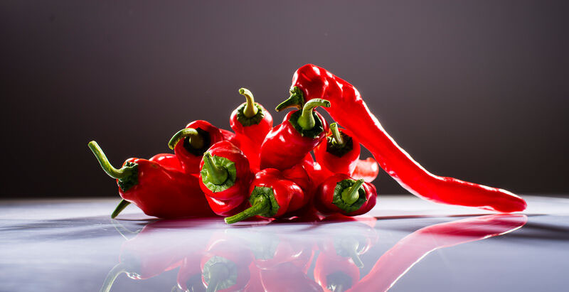 rote Spitzpaprika neben mehreren liegenden roten Spitzpaprikas