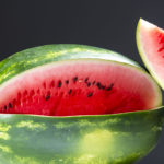 Melone an der ein herausgeschnittenes Meloenstück lehnt.