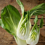 Angeschnittener, halbierter Pak-Choi vor ganzem Pak-Choi.
